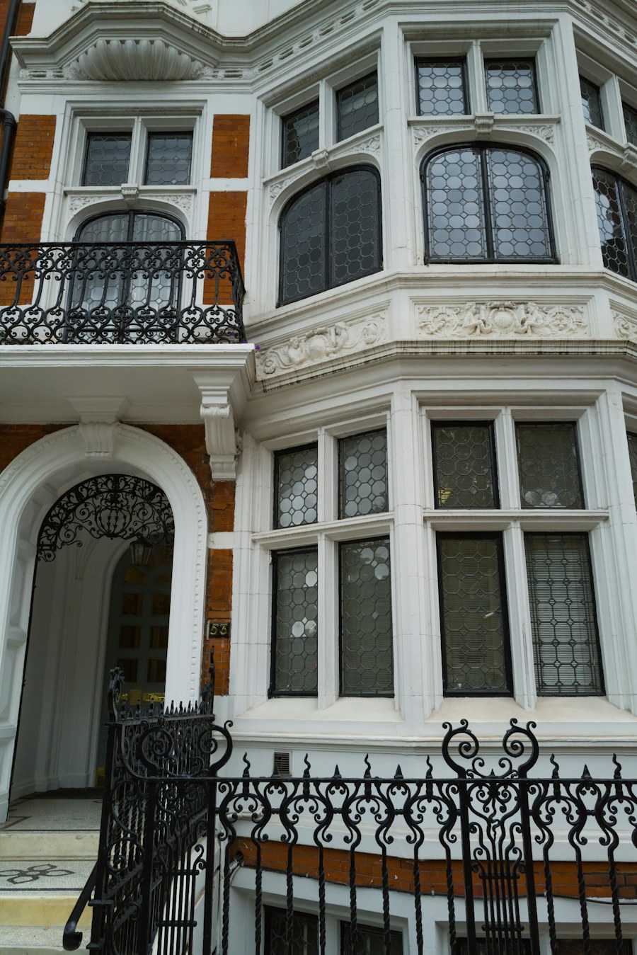 Fachada londrina com ornamentos claros, tijolos e grades trabalhadas, imagem ilustrativa